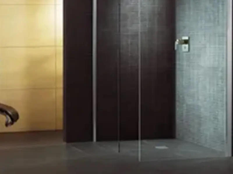 A bathroom with a black shower stall and gray tile.