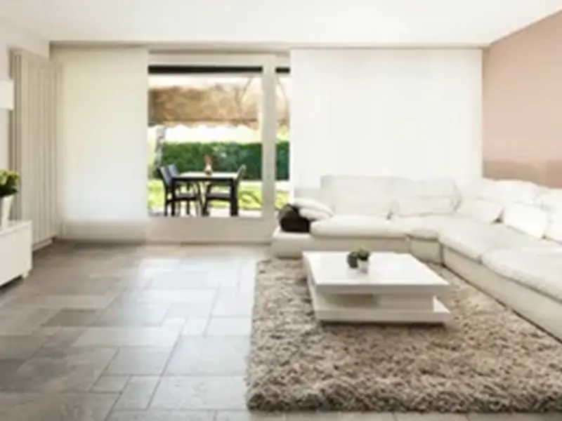 A living room with white furniture and a large rug.