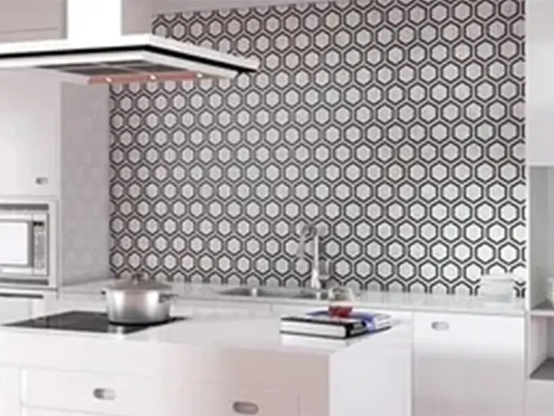 A kitchen with white cabinets and black and white tile.